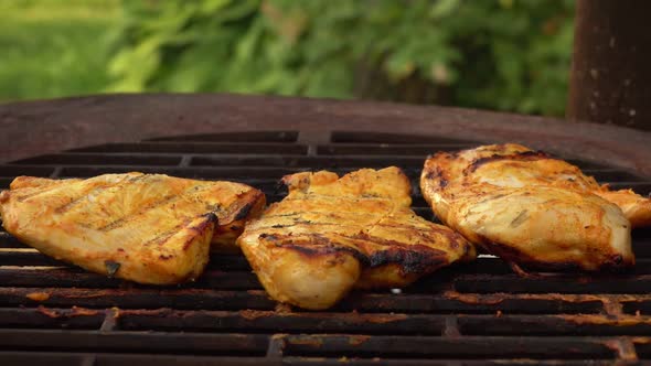 Chief Is Flipping Chicken Fillet on the Grill Grid with Kitchen Tongs Outdoors