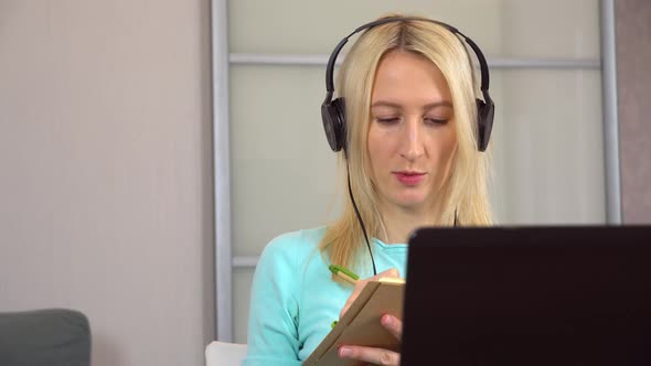 Woman Works at Home on Laptop with Headphones or Headset