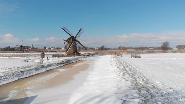 Traditional winter Dutch windmill scene and frozen canal, aerial view