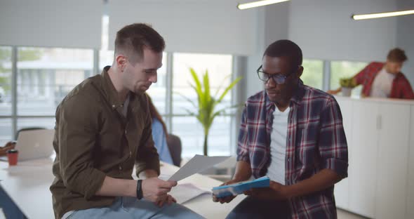 Multiethnic Business Colleagues Reviewing Paper Documents While Standing in Modern Office