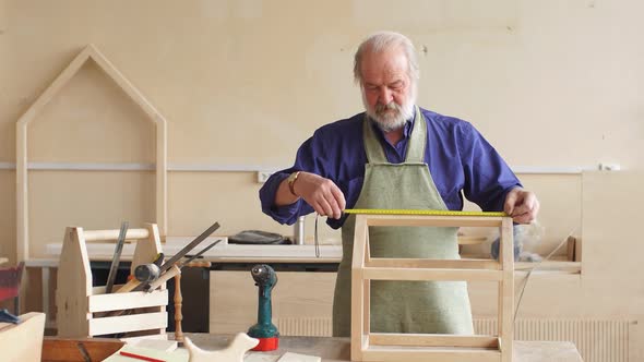 Portrait of Old Repairman Working with Wooden Board.