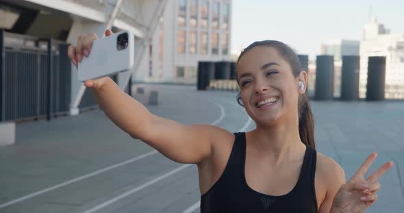 Fit Woman Runner Making Selfie Photos on Her Smartphone After Sport Fitness Training Outdoors Near