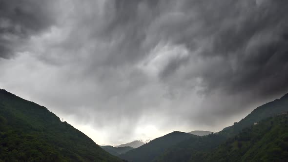 Thick Dark Stratonimbus Clouds Covered The Valley Between Forested Mountains alt