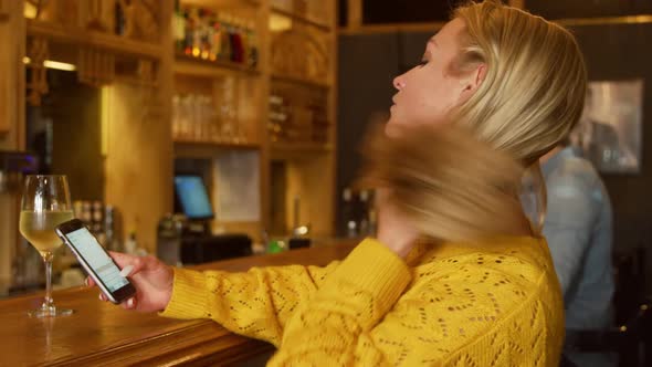 Young woman on the phone in a bar