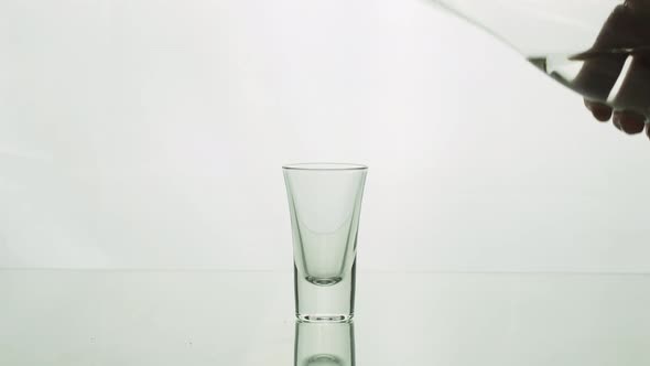 Сrystal Clear Water or Vodka Pouring From a Bottle Into a Shot
