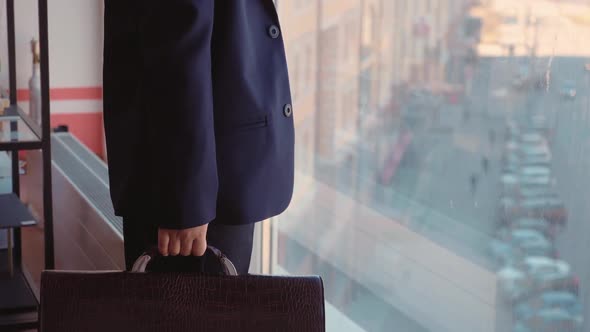 Kid Boy Boss in Suit with Briefcase in His Hand is Looking at Window in His Office