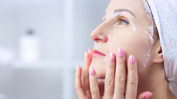 Beautiful Sexy Young Woman Applying White Textile Mask on Face Skin to Cleanse Pore