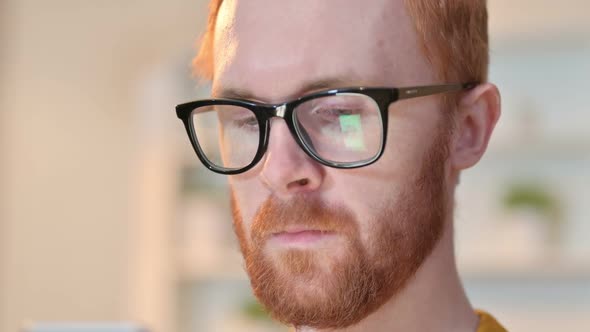 Close Up of Face of Redhead Man Using Digital Device