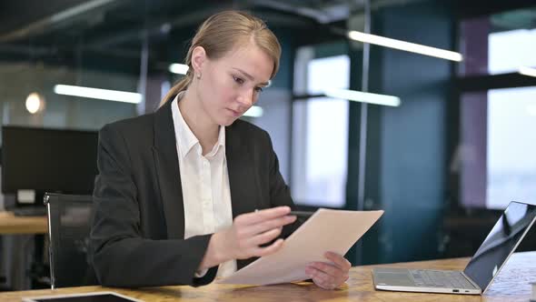 Hardworking Young Businesswoman Reading Documents in Office