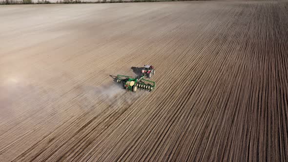 Aerial view of tractor with harrow system plowing ground on cultivated farmfield