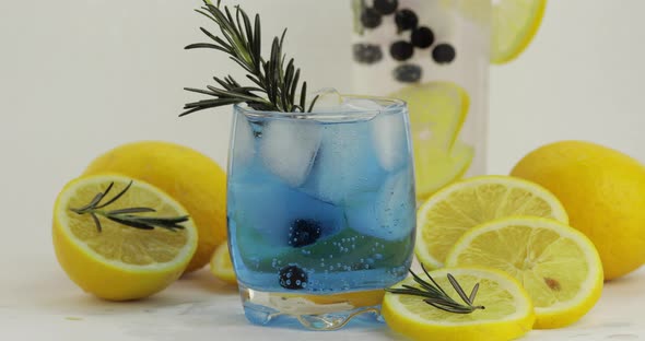 Adding Lemon Slice, Rosemary, Straw in a Glass with Soda Lemonade Blue Cocktail