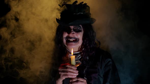 Frightening Creepy Senior Woman with Halloween Witch Makeup Looking at Candle Conjure Hex Wiz