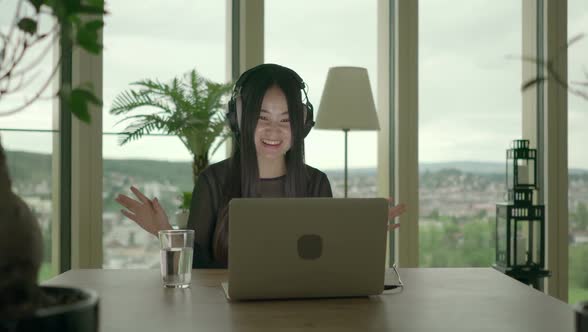 Young Asian Female Listening Music on Laptop Computer at Home
