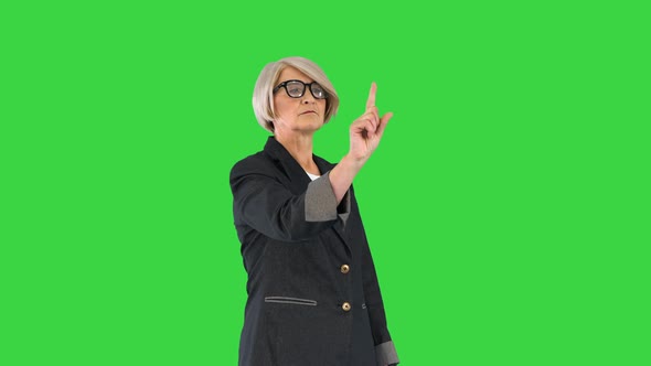 Senior Business Woman in Glasses Pointing on Buttons of a Virtual Screen on a Green Screen Chroma