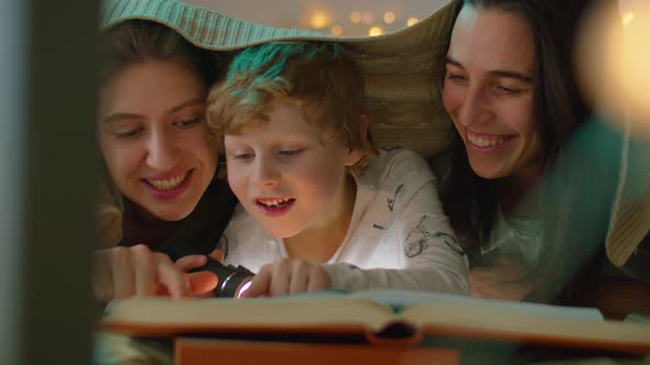 Happy Lesbian Couple Reading Book in Bed with Little Son