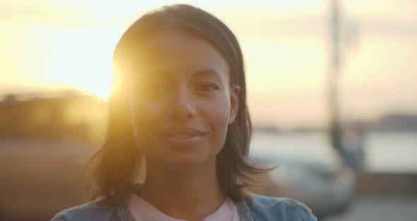 Bokeh Shot of Happy African Woman Looking at Camera Outdoors in Evening