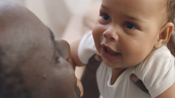 Closeup Portrait of Young African Father Hugging and Kissing Newborn Baby.