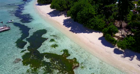 Wide angle drone travel shot of a white paradise beach and blue water background in high resolution 