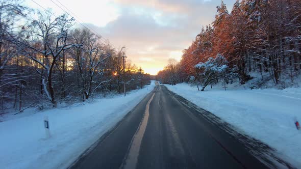 Traveling by car on a winter road at sunset