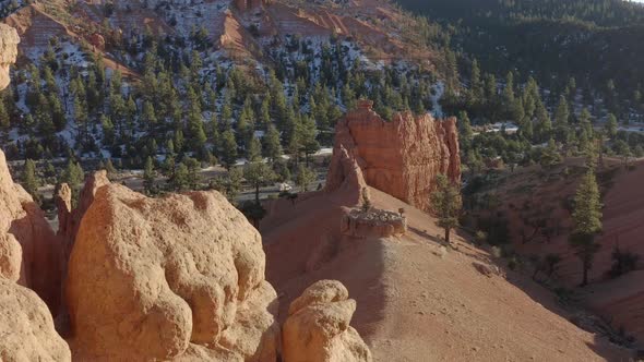 A drone shot of the sandstone rocks of Red Canyon area near Bryce Canyon in the winter and a van is