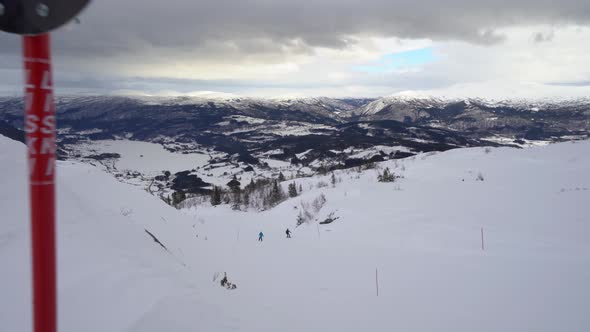 Persons in distant snowboarding down black trail at famous ski destination - Moving bacwards showing