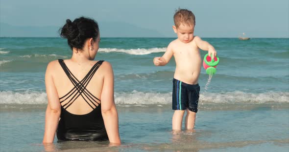 Happy and Carefree Mother and Son Play By the Sea, Sunbathe, Swim