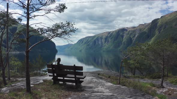 Woman relaxing on bench viewing picture perfect Sorfjorden Fjord Norway - Stanghelle western Norway