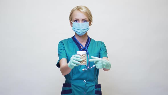 Medical Doctor Nurse Woman Wearing Protective Mask and Rubber or Latex Gloves - Holding Pills