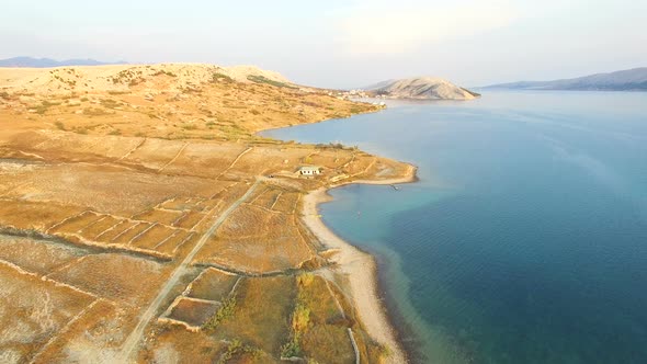 Flying above isolated house in yellow grass of Pag island, Croatia