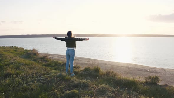 Tracking Aerial Shot of Young Woman Enjoying Sunset in Field Near the Cliff During Beatiful Sunset