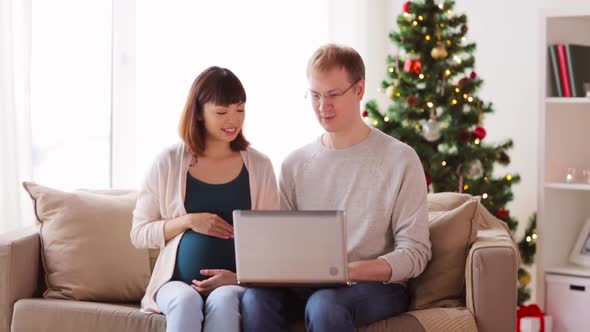 Man and Pregnant Wife with Laptop on Christmas