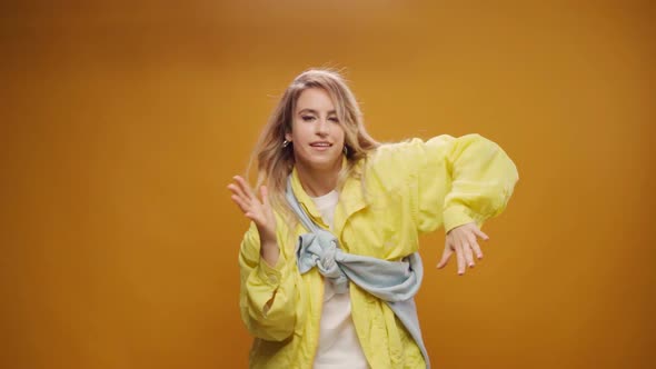 Woman Professional Dancer Dancing in Studio Against Yellow Background