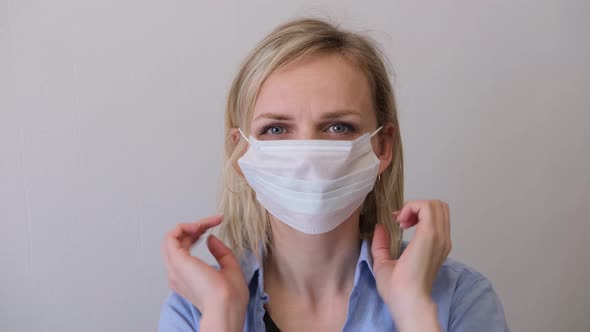 Blonde Woman Puts on Wearing Surgical Medical Face Mask Against Infectious Disease Protection