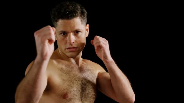 Portrait of man boxing on black background