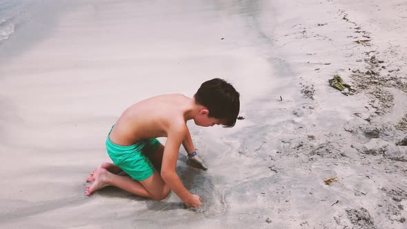 Slow motion shot of boy digging in sand, Mauritius