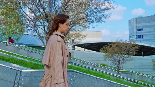 Girl in Trench Coat Descends Stairs at Street