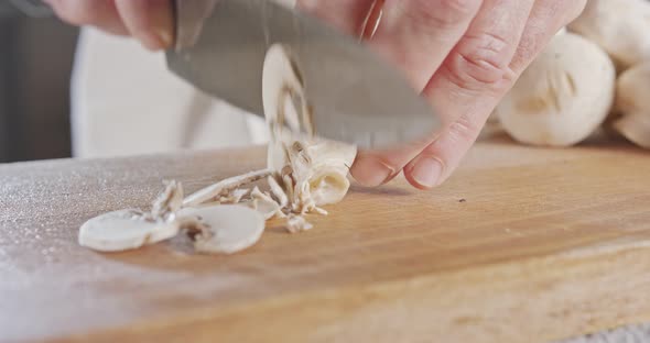 Close up of a chef knife slicing champignon mushrooms