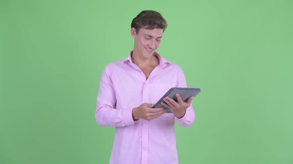 Happy Young Handsome Businessman Thinking While Using Digital Tablet