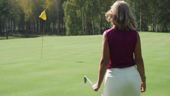 Summer Day Woman Playing Golf Walking on Golf Course in Forest Area Back View