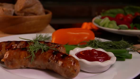 Plate with Grilled Sausages on Table Next To Fire