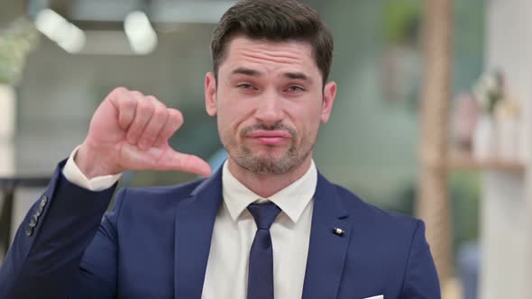 Disappointed Young Businessman Doing Thumbs Down 