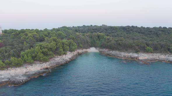 Aerial wide shot of a hidden beach on Cape Kamenjak, Croatia. Small bay framed with cliffs. Camera f