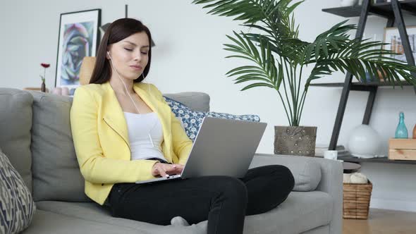 Casual Sitting Woman Listening Music on Laptop at Home