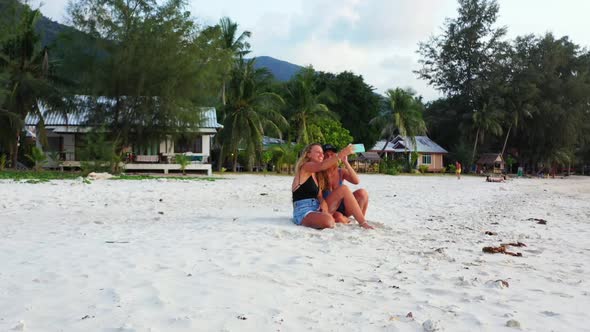 Girls tanning on beautiful lagoon beach wildlife by turquoise ocean and white sandy background of Ko