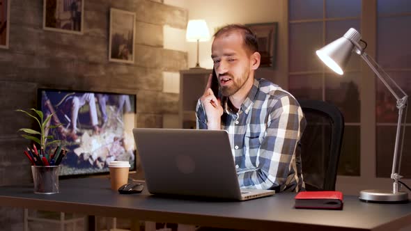 Entrepreneur Talking on Mobile Phone While Working on Laptop