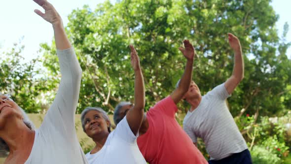 Senior friends doing stretching exercise in garden 4k