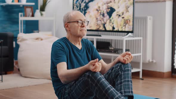 Handheld Shot of Pensioner in Lotus Position Meditating