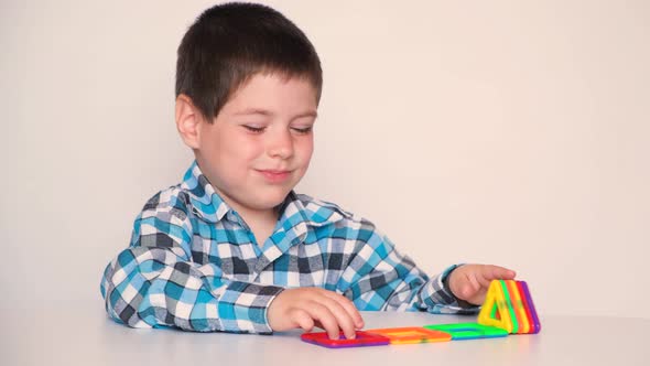 A Preschool Boy Cheerfully Plays with a Magnetic Constructor Laughs and Speaks
