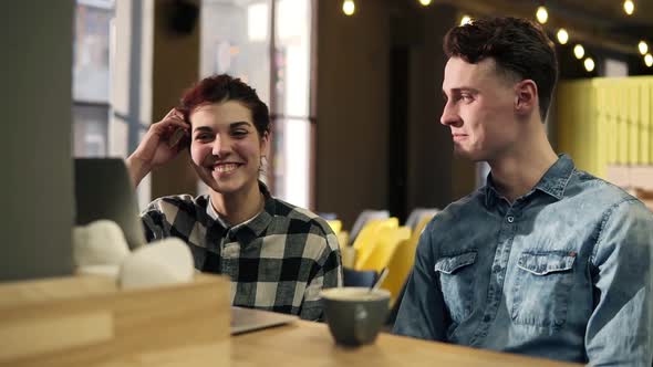 Young Couple in Stylish Hipster Urban Outfits Sitting in an Open Coworking Space Discussing