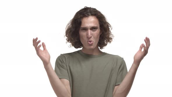 Young Guy with Wavy Hairstyle Wearing Casual Tshirt Raising Hands Up and Looking Confused Asking